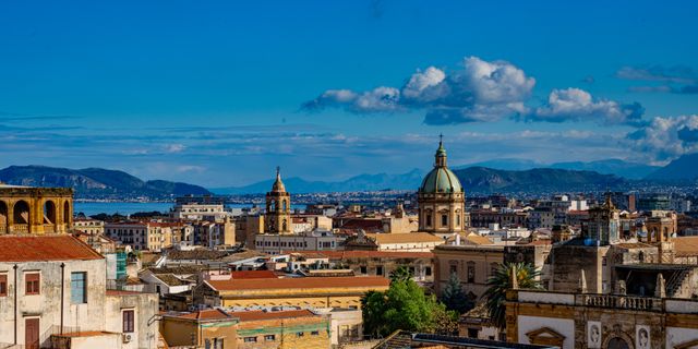 Discover the vibrant skyline of Palermo, Sicily capturing historic architecture beneath a bright blue sky.