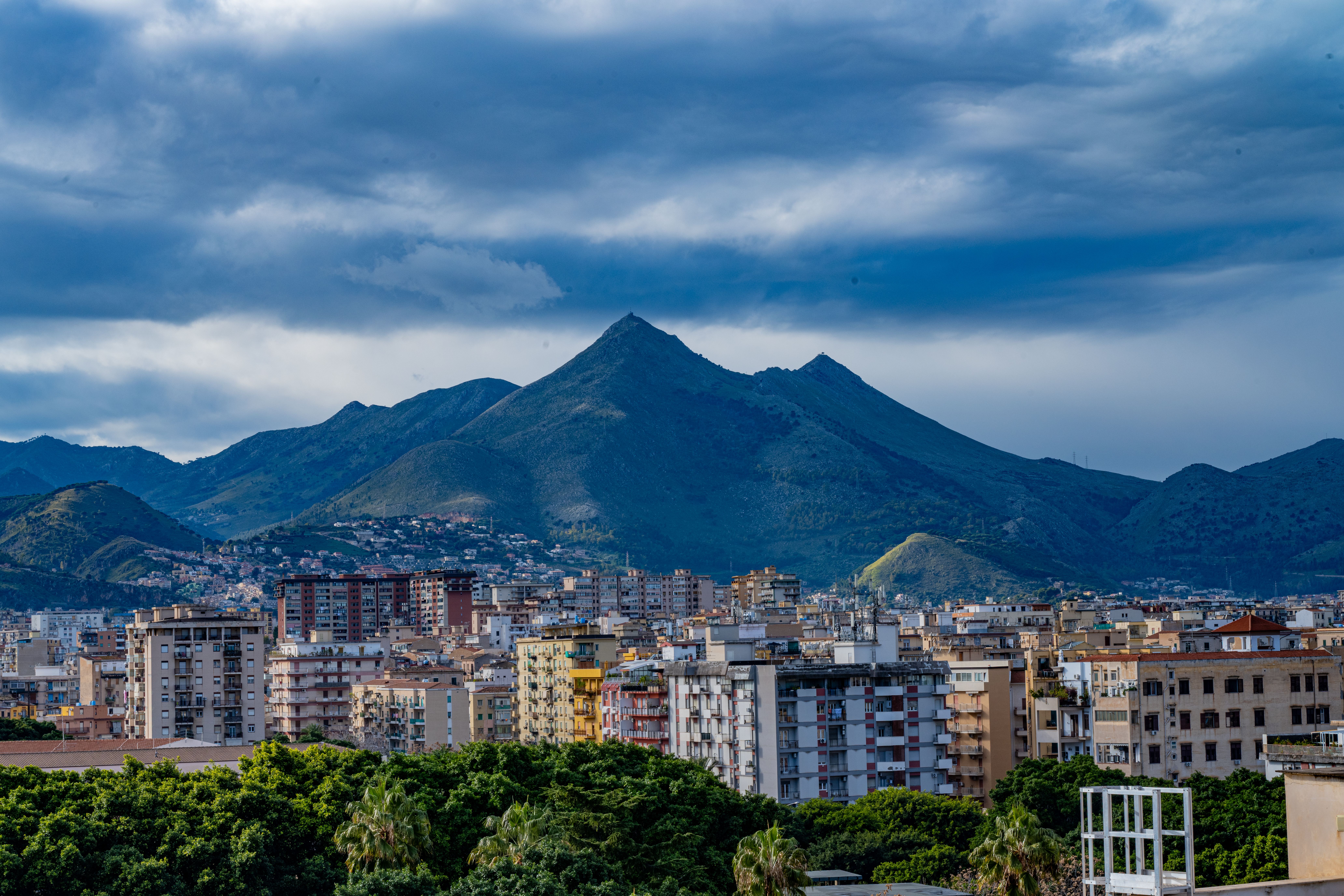 View of Palermo cityscape with majestic mountainous backdrop under dramatic cloudy sky in Sicily, Italy. View of Palermo cityscape with majestic mountainous backdrop under dramatic cloudy sky in Sicily, Italy.