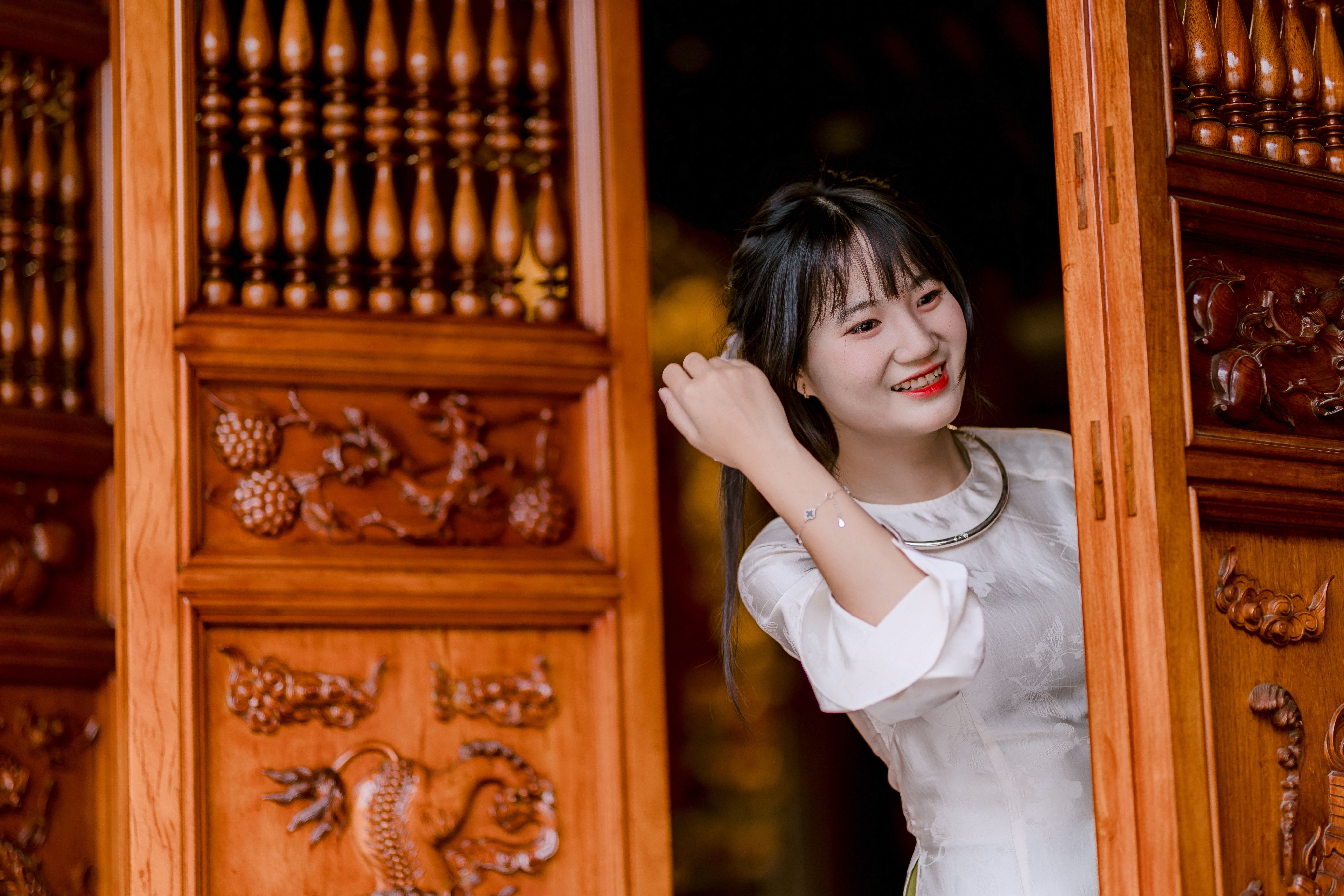 Smiling Woman in Traditional Asian Wooden Doorway · Free Stock Photo