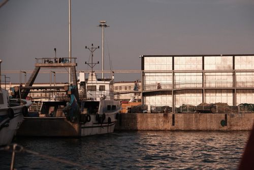 Free Fishing boats at a tranquil dock in Barcelona, capturing the serene sunset over the harbor. Stock Photo