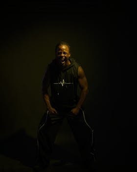 Strong man expressing power and emotion through a shout in a dramatic low-light setting.