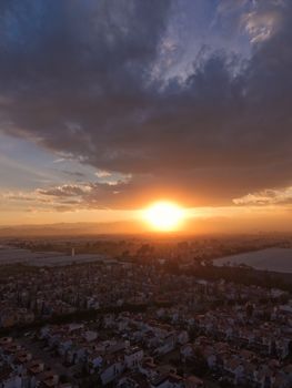 A stunning aerial view of a cityscape during sunset with dramatic clouds.