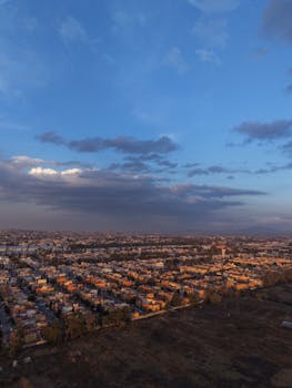 Aerial shot capturing a sprawling cityscape under a vibrant evening sky showcasing the transition to night.