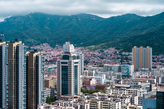 Stunning aerial view of Qingdao's modern skyline with mountains in the backdrop.