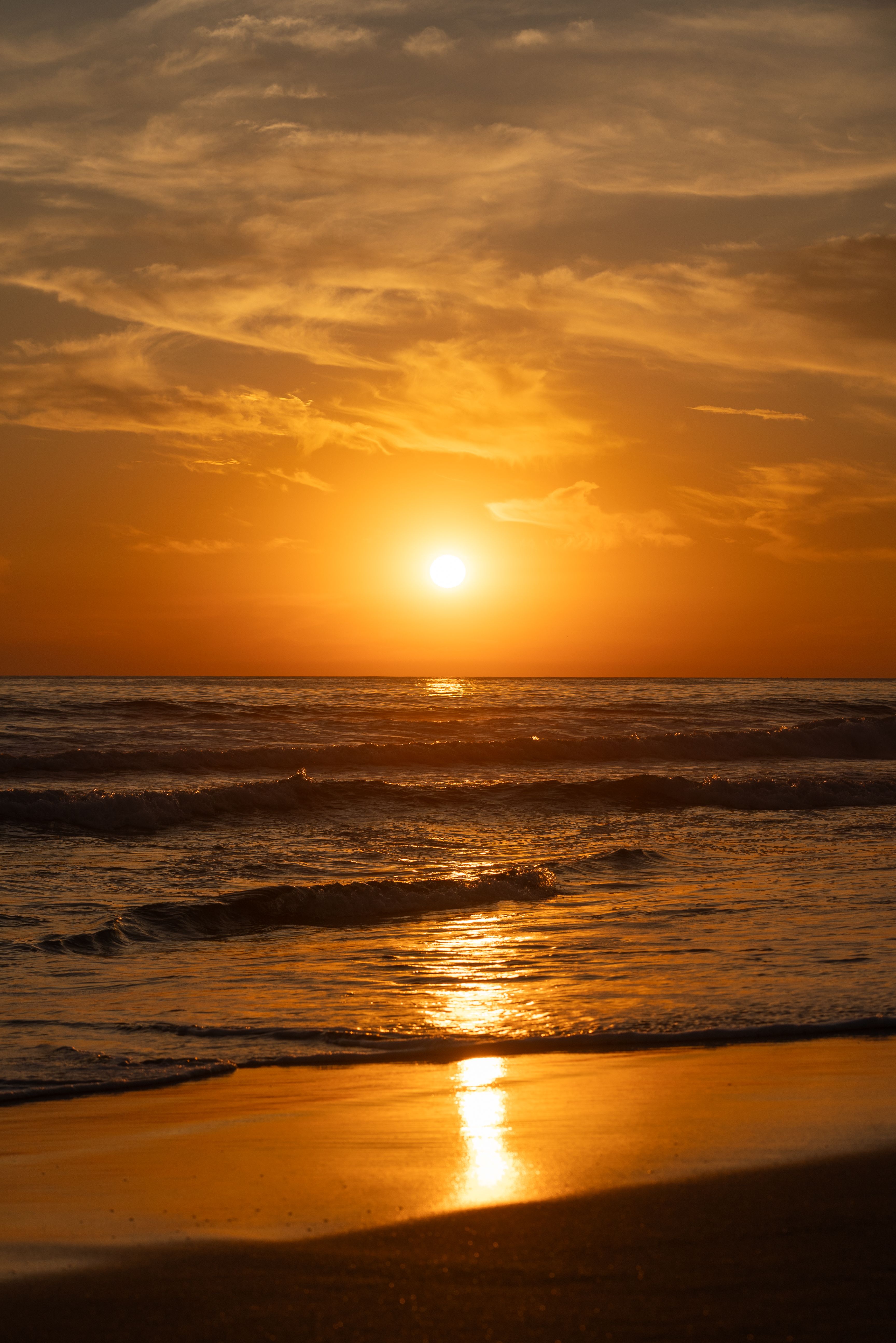 Capture the serene beauty of a beach sunset in El Salvador with golden reflections on the waves.