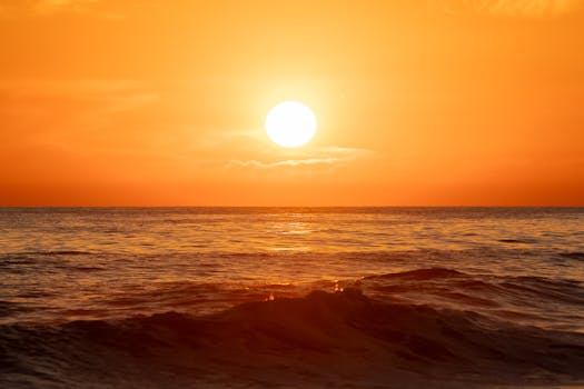 Stunning sunset view with vibrant orange hues over ocean waves in El Salvador, captured during golden hour.