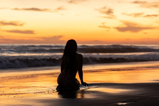 Silhouette of a person sitting on El Salvador beach during a beautiful sunset.