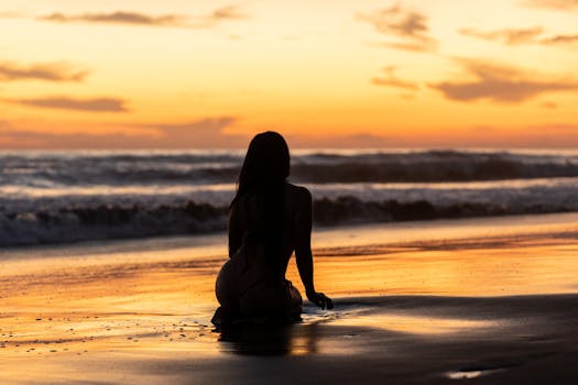 A serene silhouette enjoying the vibrant sunset on a sandy beach in El Salvador.