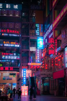 A bustling urban street scene illuminated by colorful neon lights in an Asian city at night.