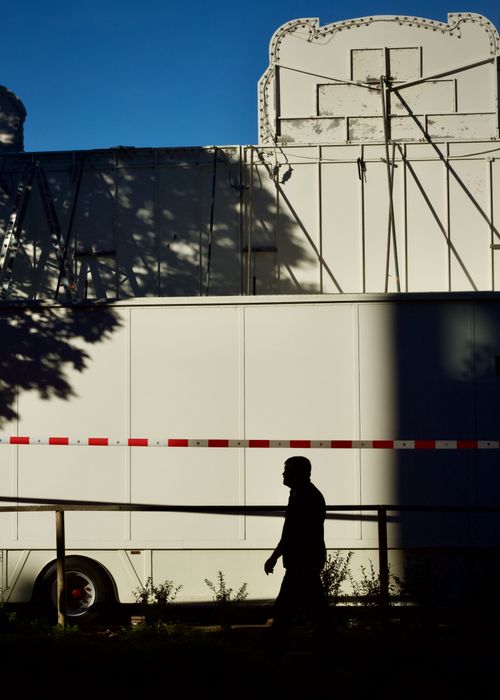 Free Silhouette of a man walking past a fairground ride trailer under dramatic evening light. Stock Photo