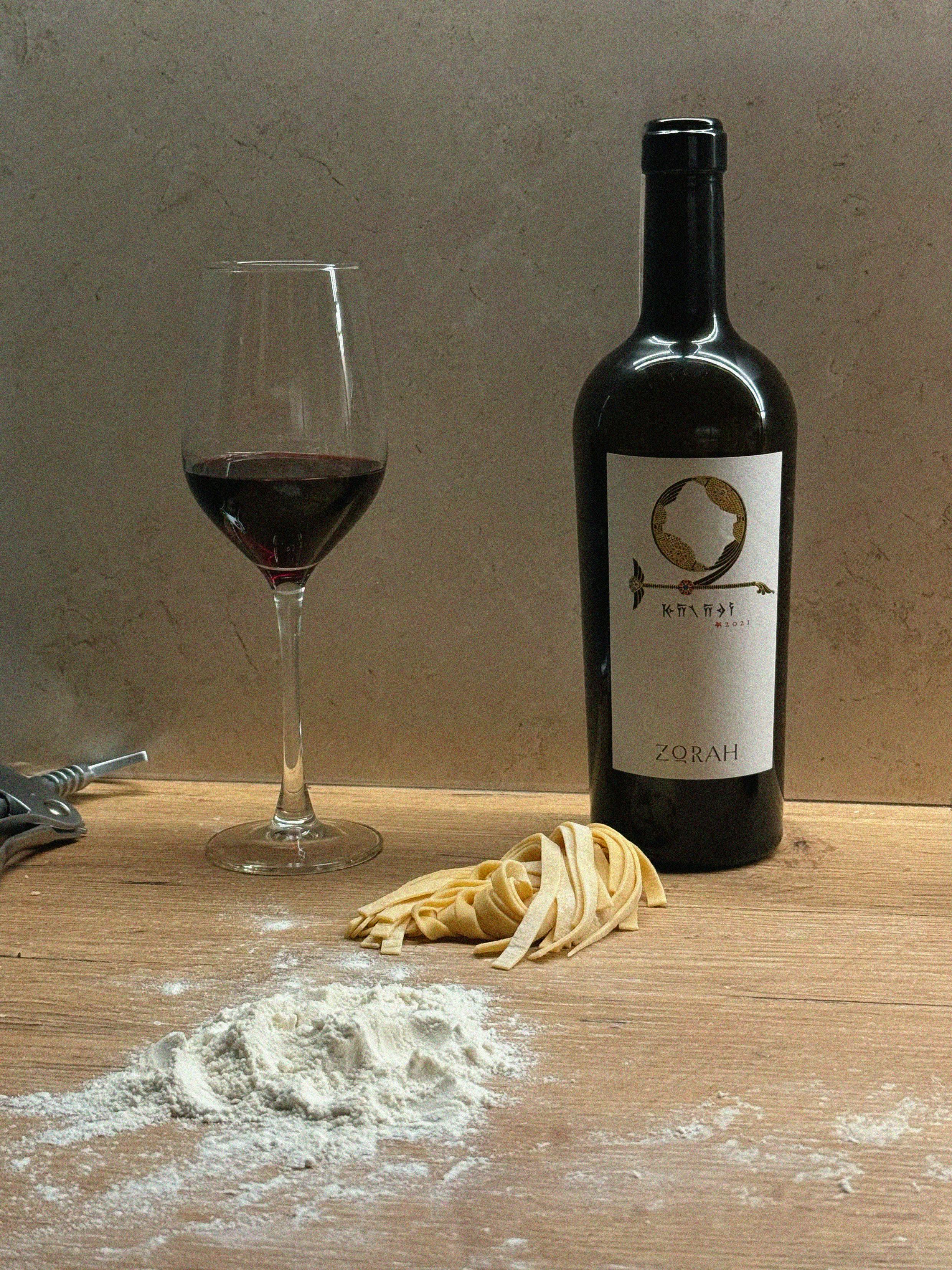 A bottle of wine in a bag with grapes and an empty glass on a rustic table, ideal for culinary themes. - Photo by Cup of  Couple on Pexels