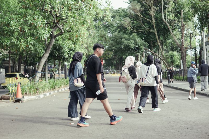 A group of people enjoying a casual walk through a park in Jawa Barat, Indonesia on a sunny day.