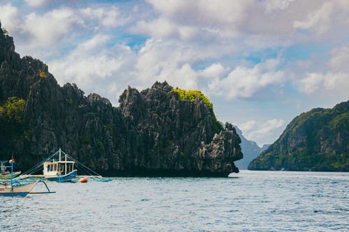 Free A picturesque view of limestone cliffs in El Nido, Philippines, with traditional boats on a sunny day. Stock Photo