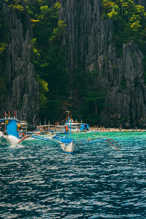 Free Picturesque seaside view with blue traditional boats near limestone cliffs and tropical waters. Stock Photo