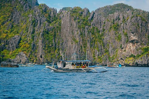 Free A traditional Filipino boat navigating the waters of El Nido with dramatic limestone cliffs in the background. Stock Photo