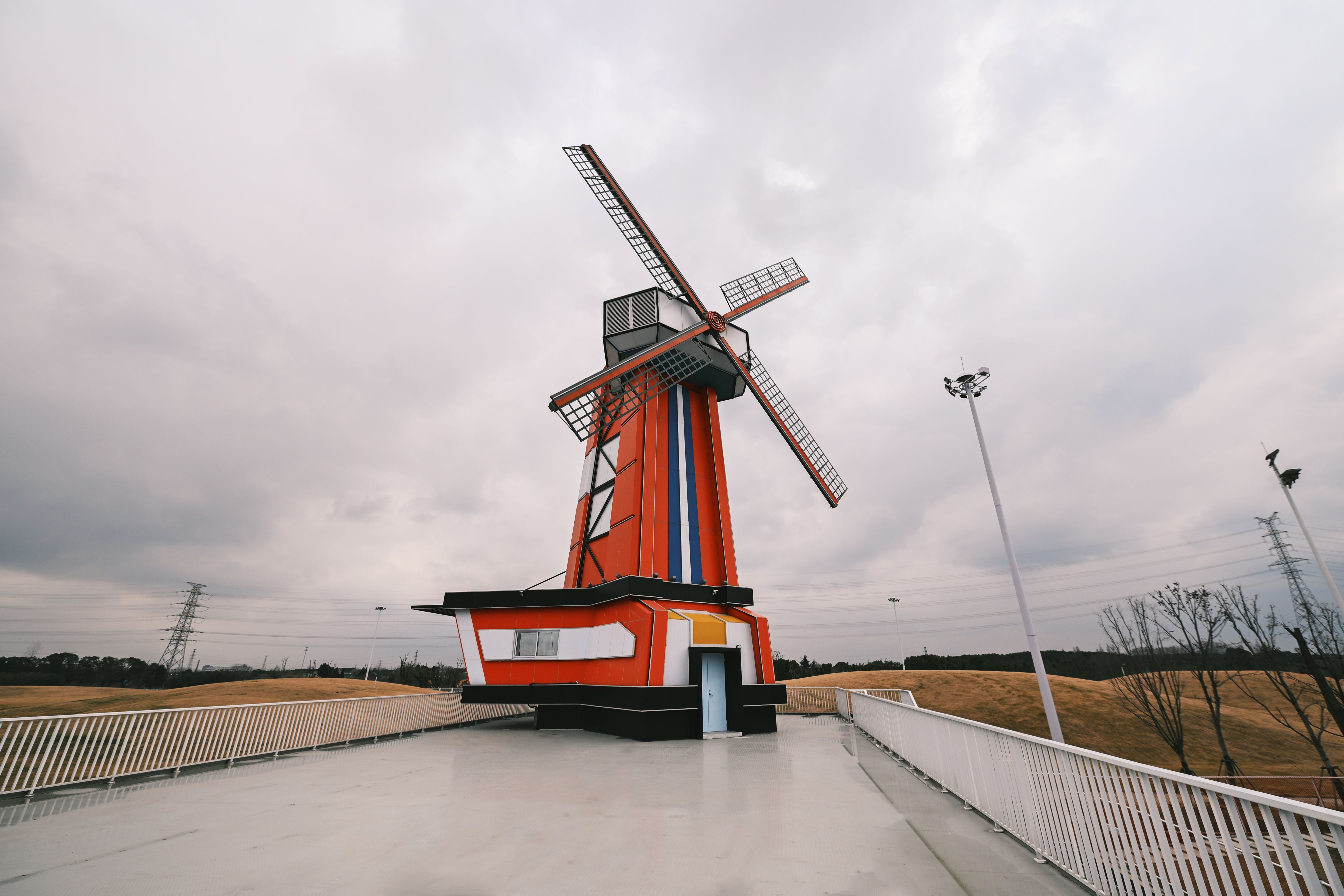 Vibrant Red Windmill Against Cloudy Sky · Free Stock Photo