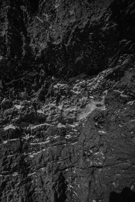 Detailed black and white close-up of a rugged rock surface highlighting textures and contrasts.