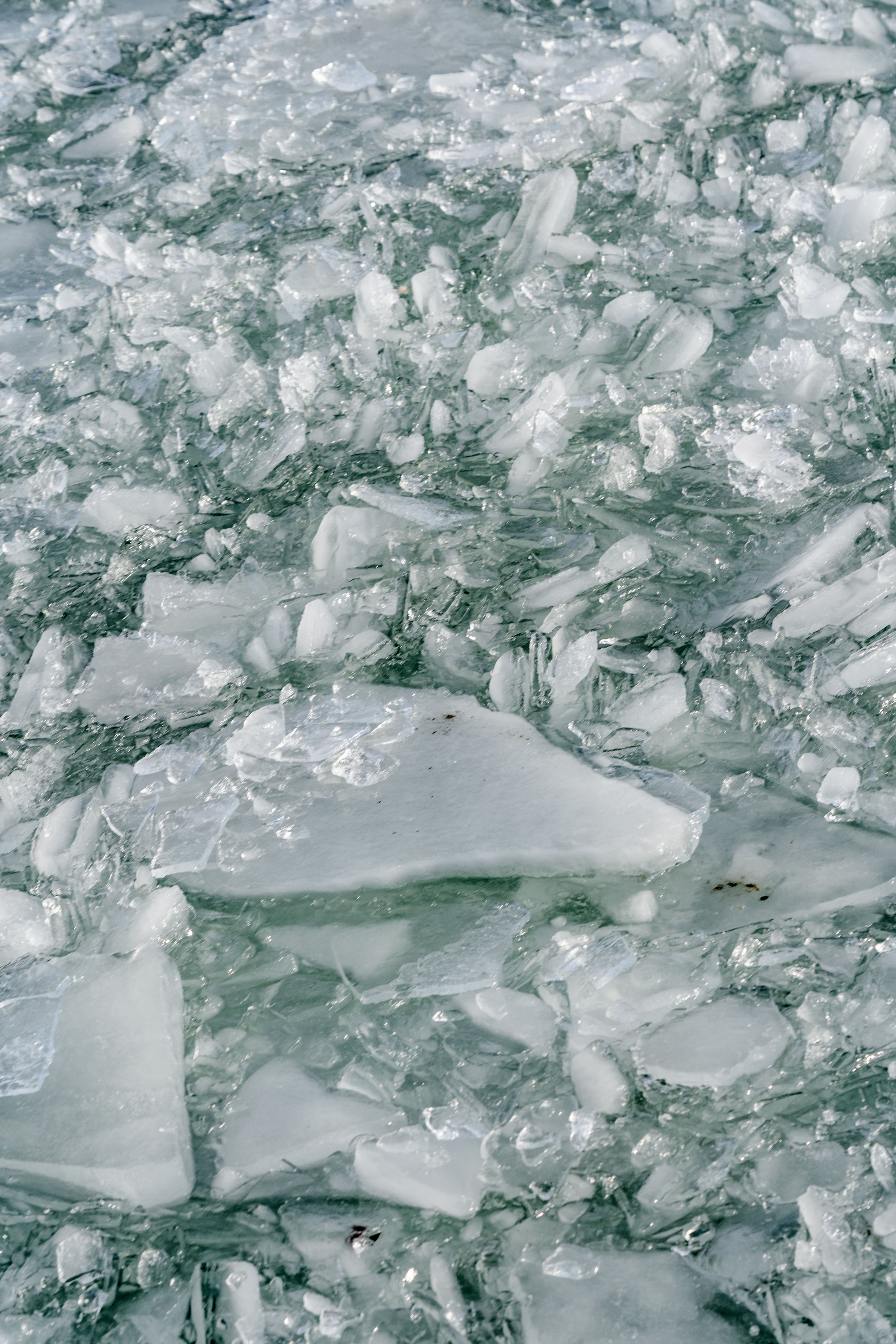 Abstract texture of frozen ice chunks on a lake, highlighting geometric shapes and crystalline structures.