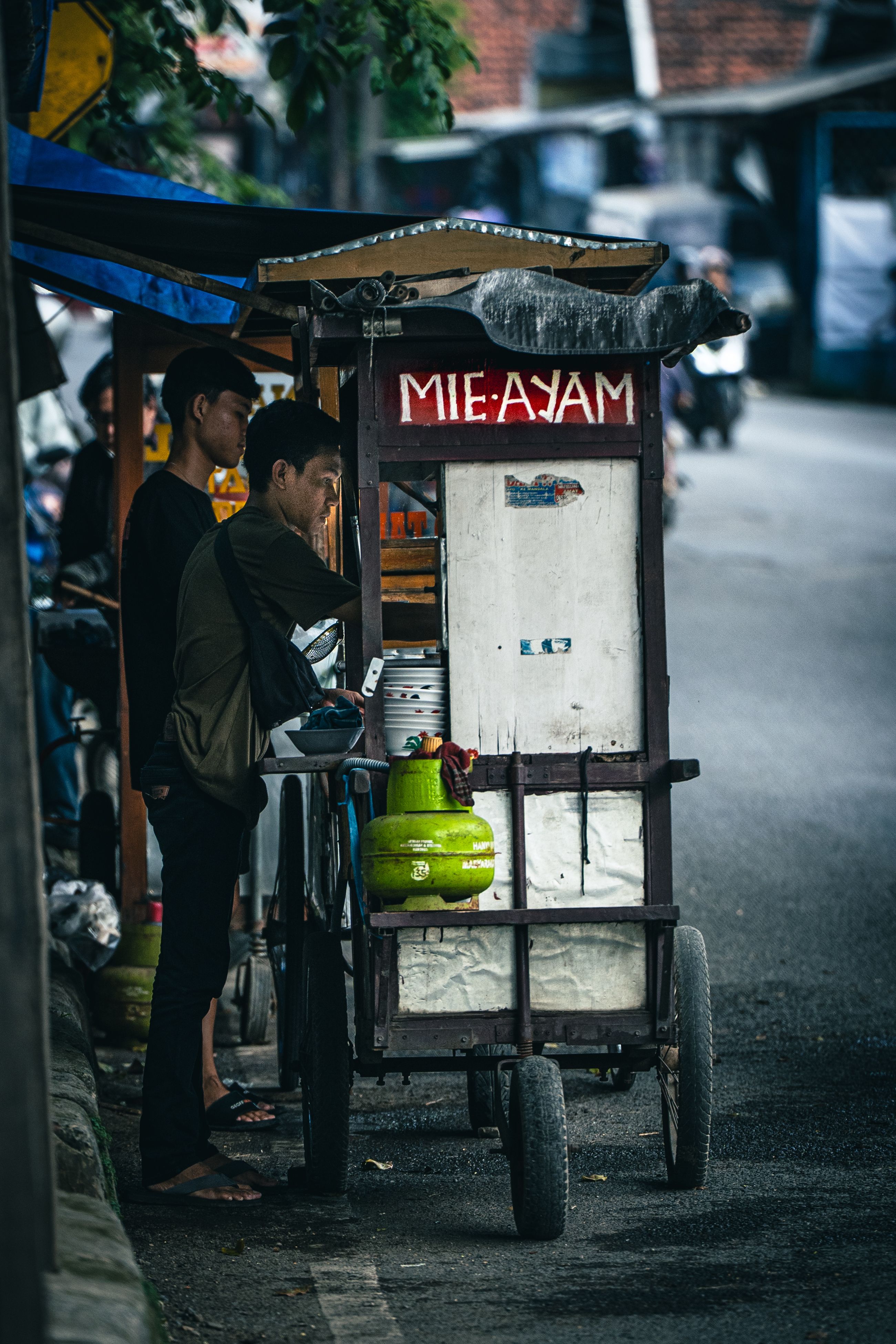 A street vendor prepares mie ayam in a traditional cart in Subang, Indonesia.