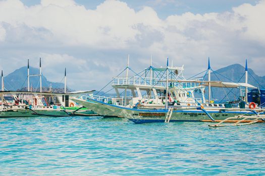 Colorful outriggers in a serene Filipino harbor with mountain views.