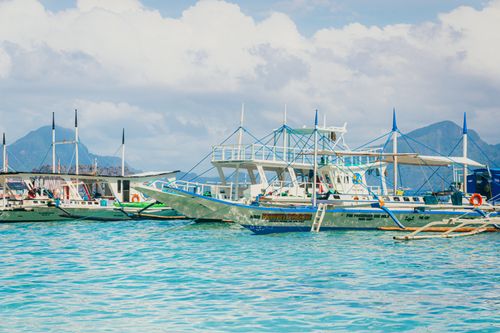 Free Colorful outriggers in a serene Filipino harbor with mountain views. Stock Photo