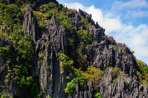 Free Dramatic limestone cliffs covered with lush greenery under a clear blue sky. Stock Photo