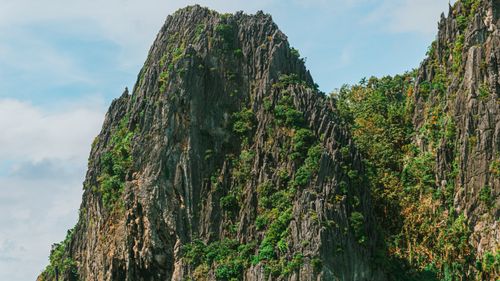 Free Towering limestone cliffs with vibrant greenery against a clear sky in a tropical setting. Stock Photo