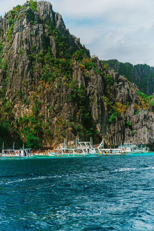 Free Vibrant tropical scene with boats near the stunning limestone cliffs of El Nido, Palawan. Stock Photo