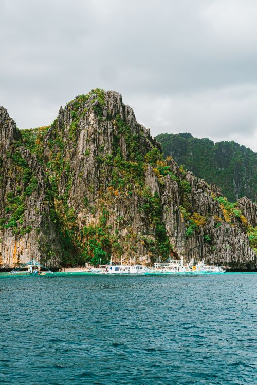 Free Vibrant limestone cliffs and traditional boats in El Nido, Palawan, Philippines under a cloudy sky Stock Photo