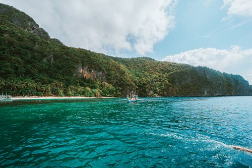 Free Scenic view of a tropical island with lush greenery and clear blue waters under a bright sky. Stock Photo