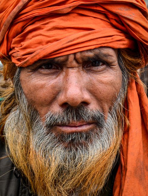 Free Close-up portrait of an elderly man in an orange turban, showcasing his intense gaze and weathered features. Stock Photo
