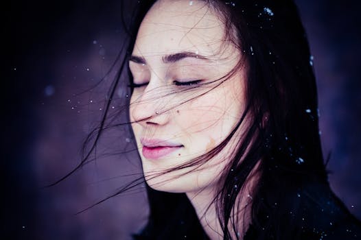 一位闭着眼睛的女子，在宁静的雪景中，发丝轻扬