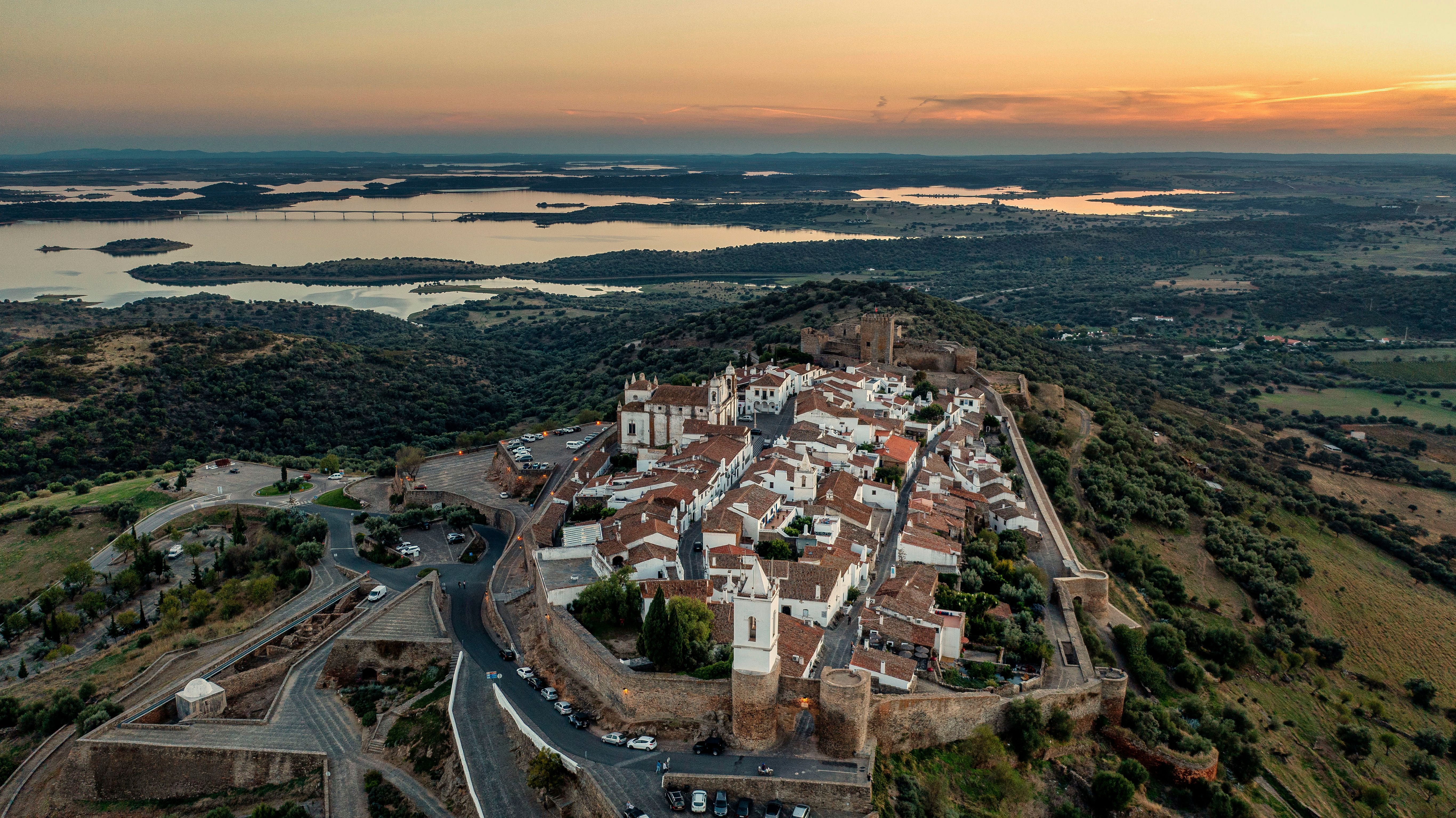 Whitewashed stone houses of Monsaraz walled village glowing under warm golden sunset over Alentejo plains