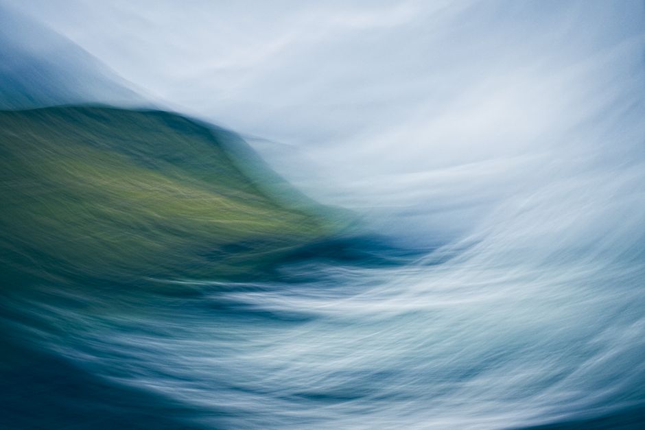 Abstract seascape of Faroe Islands showcasing blue and green hues, capturing wave motion and coastal landscape.