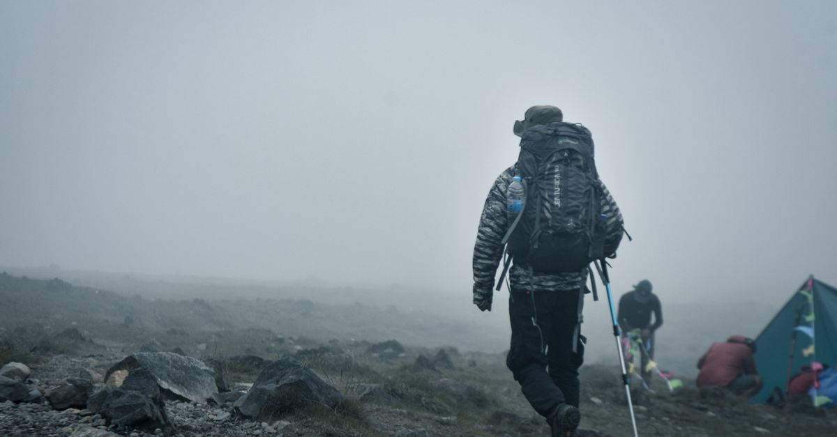 hiker with trekking gear standing on a rocky outcrop overlooking the Volta Region landscape
