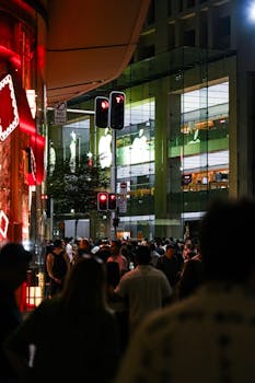 Vibrant city street at night, bustling with people under neon lights and traffic signals.