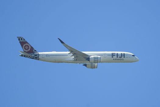 Fiji Airways Airbus A350 flies against a clear blue sky, showcasing its unique livery.