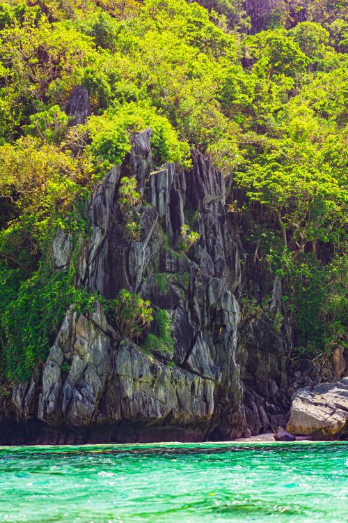Free Breathtaking view of a lush green cliff by turquoise waters, perfect for nature lovers. Stock Photo