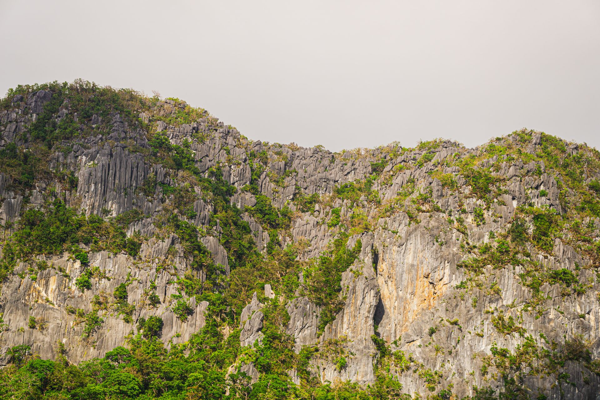 Limestone karst mountains surrounded by green hills in Laos in daylight.