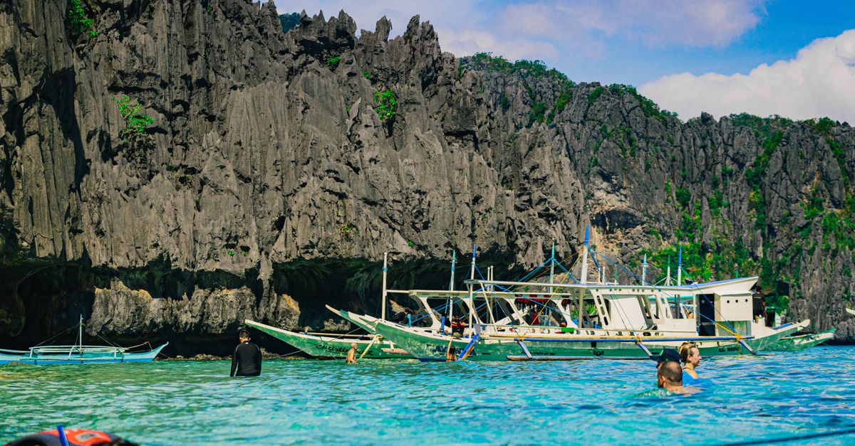 A stunning view of traditional boats in a tropical lagoon with limestone cliffs.