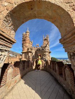 A woman in a yellow dress explores the architectural beauty of Castillo de Colomares.