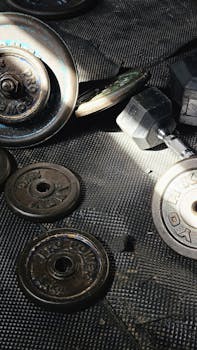A collection of vintage weight plates and dumbbells on a textured gym floor highlighting fitness.