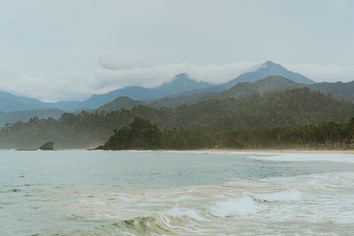 Free Serene coastal landscape with mountains and gentle waves, evoking a peaceful vibe. Stock Photo