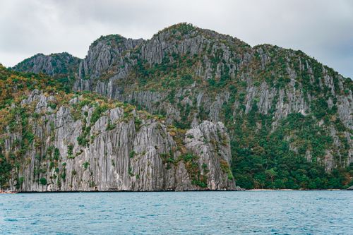 Free Stunning limestone cliffs with lush greenery by the blue ocean, creating a serene natural landscape. Stock Photo