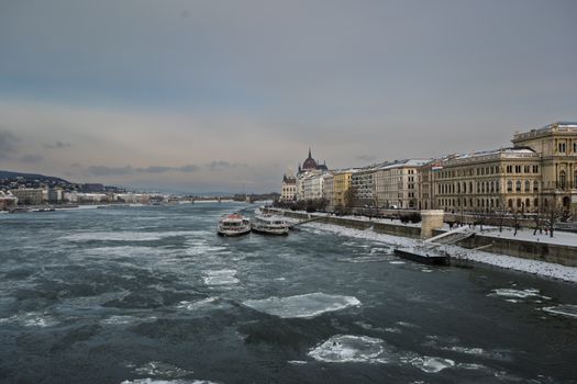 Scenic winter view of Budapest Parliament along the icy Danube River.
