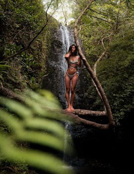 在夏威夷茂密的森林中，一名女子身着比基尼在瀑布旁摆姿势