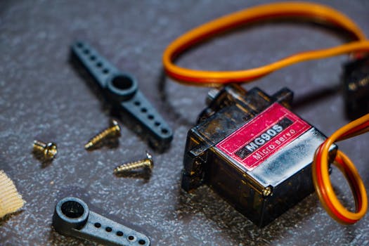 Detailed view of an MG90S micro servo motor with screws and components for robotics applications.