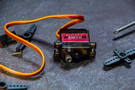 Detailed image of MG90S micro servo motor and its components on a workbench, ideal for robotics projects.