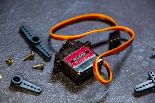 Close-up of MG996R micro servo motor with accessories on textured surface.