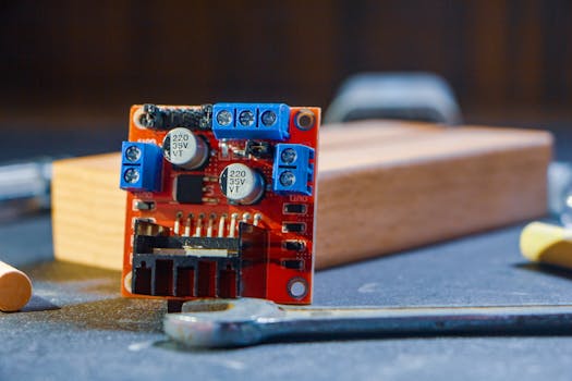 Close-up view of a circuit board with tools, featuring electronic components in a workshop setting.